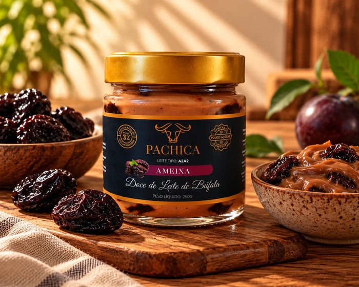 Pote de doce de leite de búfala Pachica Ameixa, 250 g, sobre tábua de madeira, com ameixas secas e uma ameixa fresca ao fundo