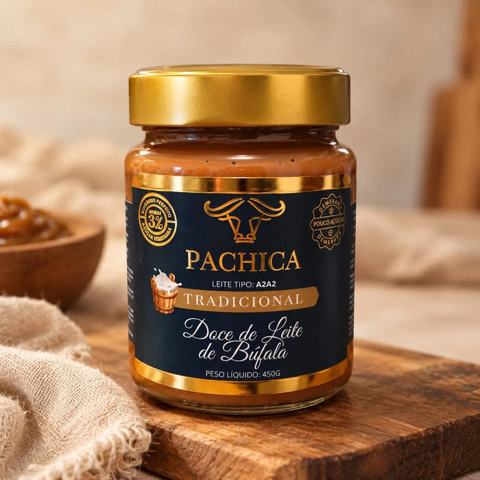 Pote de doce de leite de búfala Pachica Tradicional, 450 g, com selo de 3%, sobre tábua de madeira, com uma tigela de doce e linho ao fundo
